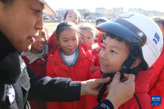 12月2日，在河北省唐山市豐潤(rùn)區(qū)迎賓路小學(xué)，民警教學(xué)生如何正確佩戴頭盔。新華社發(fā)（朱大勇攝）