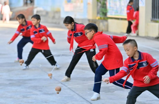 在廣西梧州市大橋小學(xué)，學(xué)生們在體育課上練習(xí)打陀螺（2024年10月25日攝）。新華社記者 黃孝邦 攝