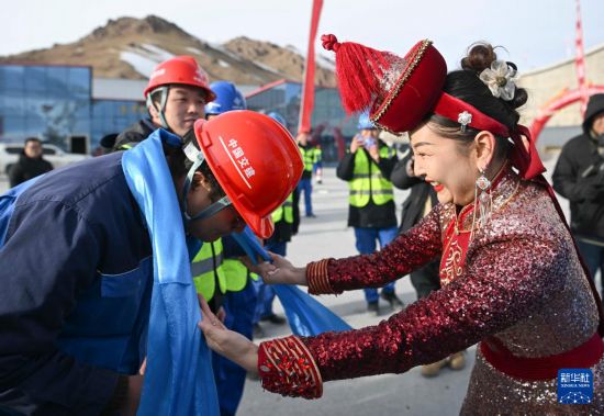 12月30日，在位于新疆和靜縣的天山勝利隧道出口，和靜縣烏蘭牧騎隊(duì)演員（右）向施工方代表敬獻(xiàn)哈達(dá)。新華社記者 胡虎虎 攝